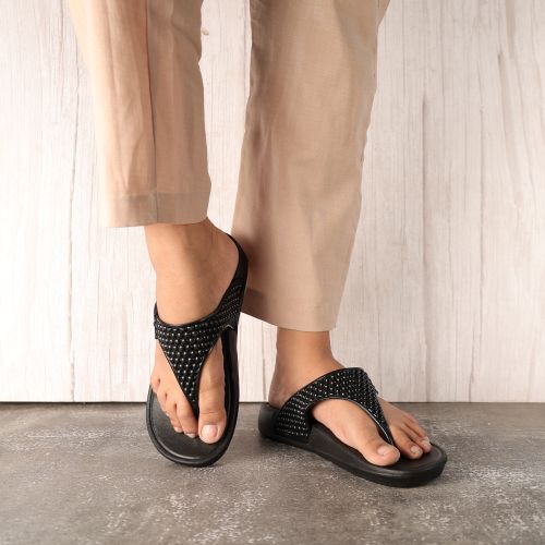 Free Black studded sandals paired with beige trousers, displaying modern footwear style. Stock Photo