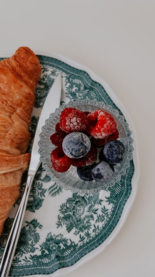 A plate with a croissant and berries on it