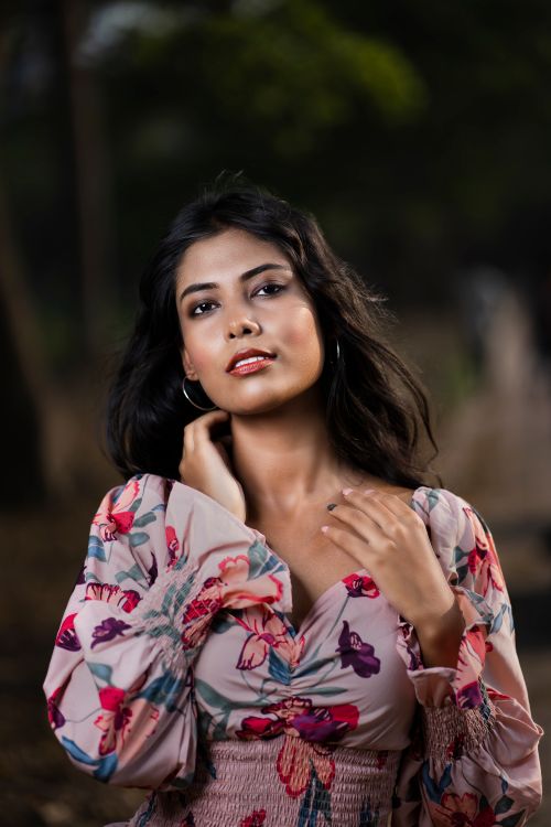 Free Portrait of a woman in a floral dress posing outdoors with soft lighting. Stock Photo