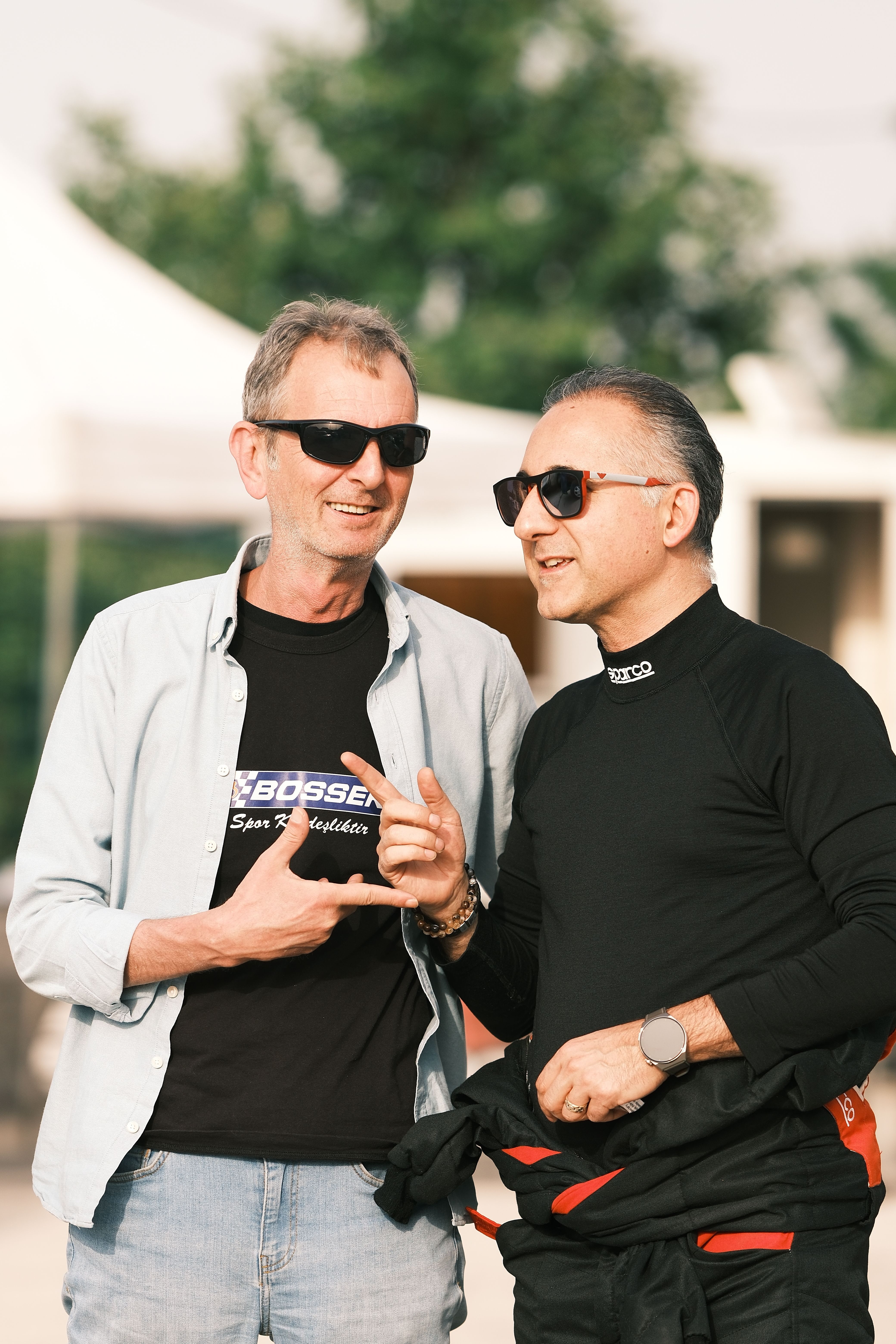 Two men wearing sunglasses having a conversation outside in Bursa, Türkiye.