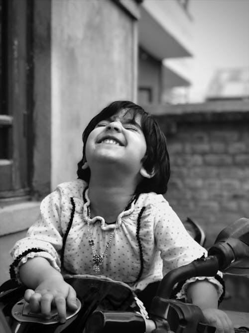 A black and white photo of a little girl laughing