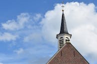 一座经典的教堂，尖顶高耸，十字架矗立，映衬着充满活力的蓝天与白云