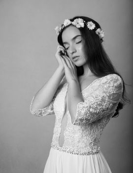 Black and white portrait of a bride in a lace wedding dress with floral headpiece.