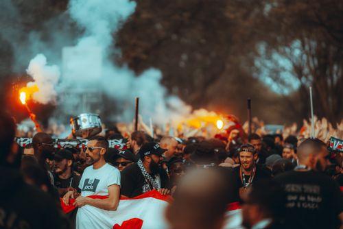 Free Energetic crowd of football fans with smoke flares and flags on a city street. Stock Photo