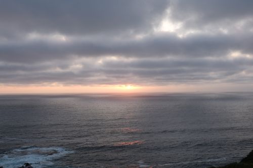 Free A peaceful ocean view at sunset with overcast skies and a calm sea reflection. Stock Photo