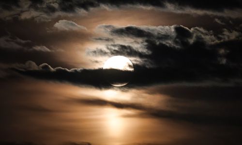 Free Breathtaking evening sky with a full moon partly obscured by dramatic clouds. Stock Photo