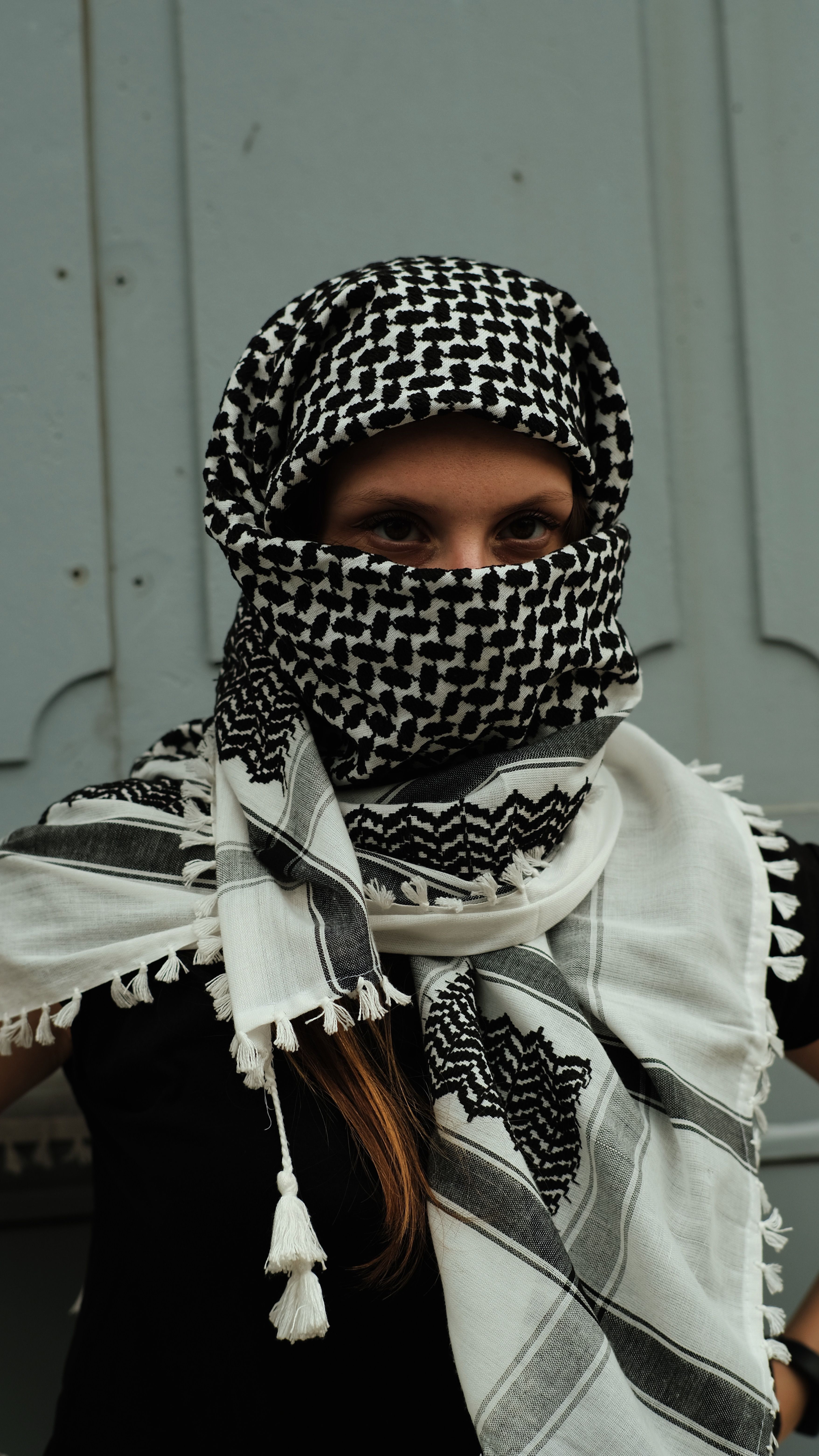 A close-up portrait of a woman posing in a traditional patterned headscarf with intricate designs.