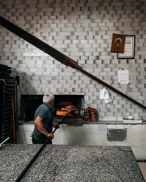 A man is standing in front of a brick oven