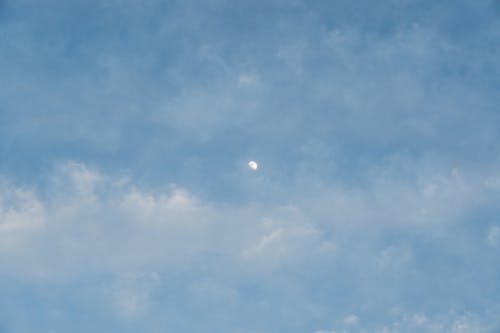 Moon in the blue sky with cotton clouds.