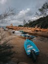 在多云的天空下，一艘蓝船停靠在岩石海边，捕捉到宁静的沿海景观