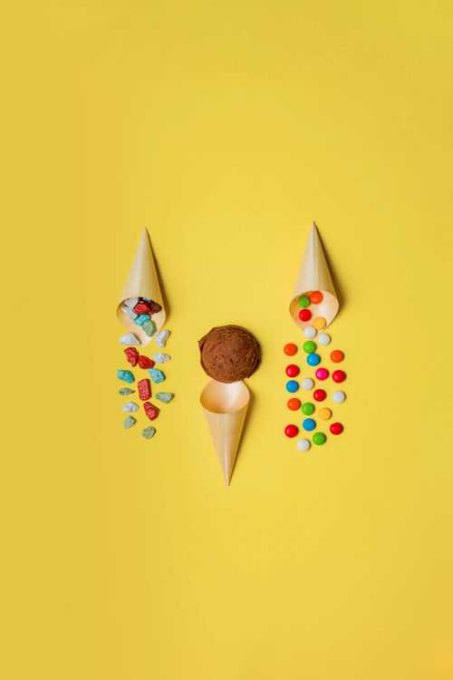 Free Three ice cream cones with toppings on a vibrant yellow background. Stock Photo