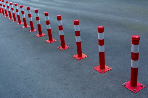 A row of red and white poles in the middle of a parking lot