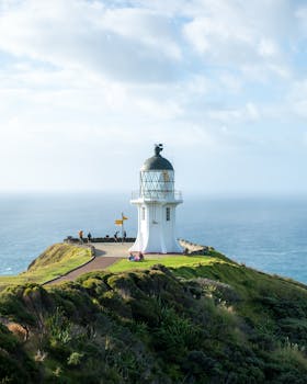 Scenic view of Cape Reinga Lighthouse in Northland, New Zealand, perched on a cliff by the sea.
