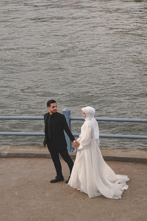 Free Bride and groom walking by the sea, exuding newlywed joy. Stock Photo