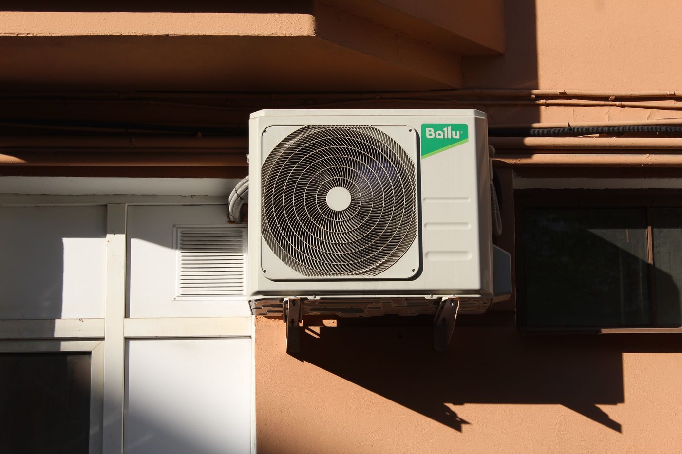 Outdoor air conditioning condenser unit mounted on a building wall