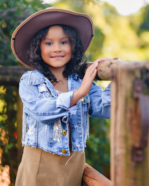 A little girl in a hat and jacket posing for a portrait