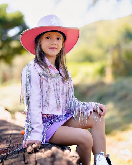 A little girl in a pink cowboy hat and fringed skirt
