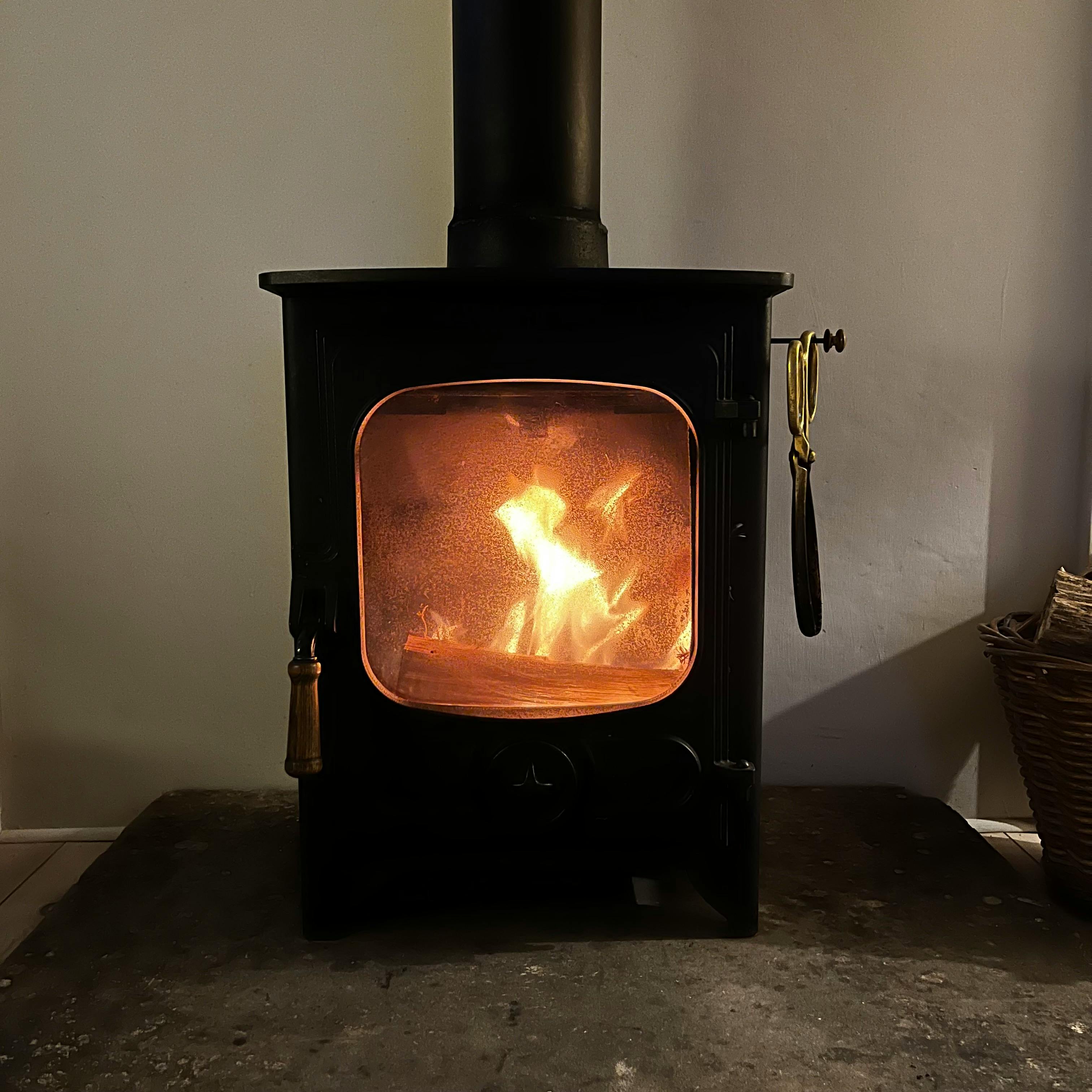 A warm and inviting wood stove with a gentle flame, perfect for cold evenings indoors.