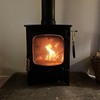 A warm and inviting wood stove with a gentle flame, perfect for cold evenings indoors.