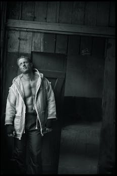 一张时尚的黑白肖像中，一个男人靠在门口，展现着时尚感