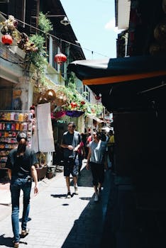 阳光明媚的日子里，游客们在一个热闹的街头市场游览，那里装饰着五颜六色的饰物和传统灯笼