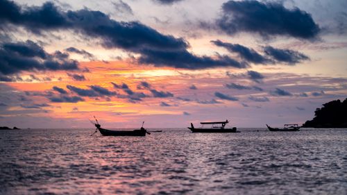 Free Beautiful sunset over the sea with silhouetted fishing boats on a calm coastal horizon. Stock Photo