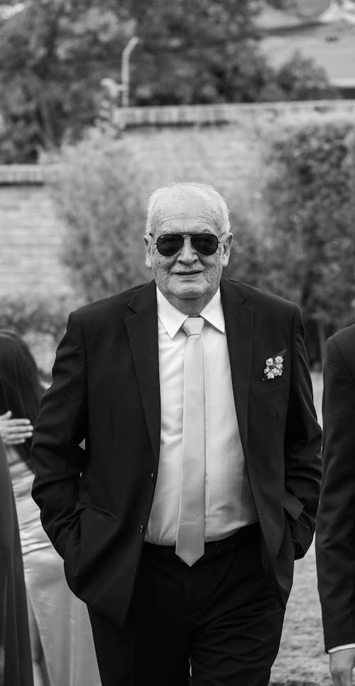 Black and white photo of a man in sunglasses walking down the aisle