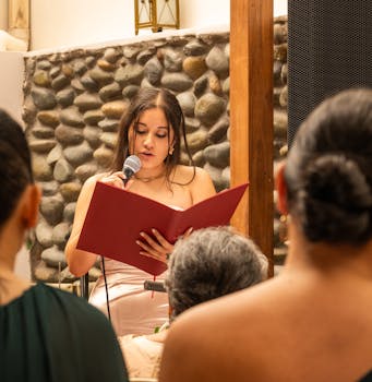 A young woman reads from a book during a ceremony, surrounded by a rocks wall in Cuenca, Ecuador.