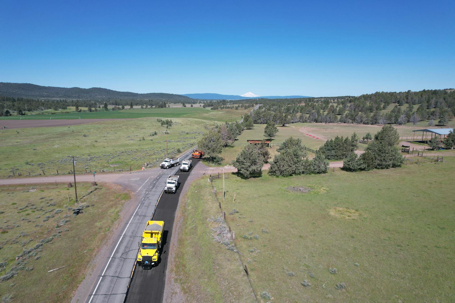 Aerial shot of a rural road with trucks in Calneva, California under a clear sky.