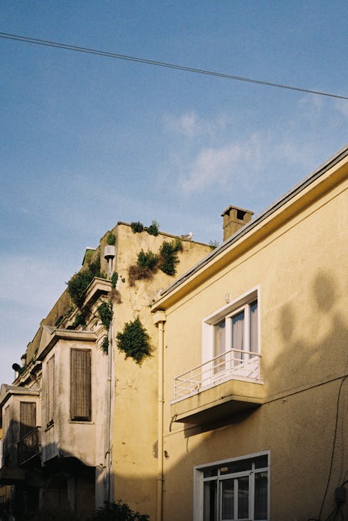 A yellow building with a green roof and a balcony