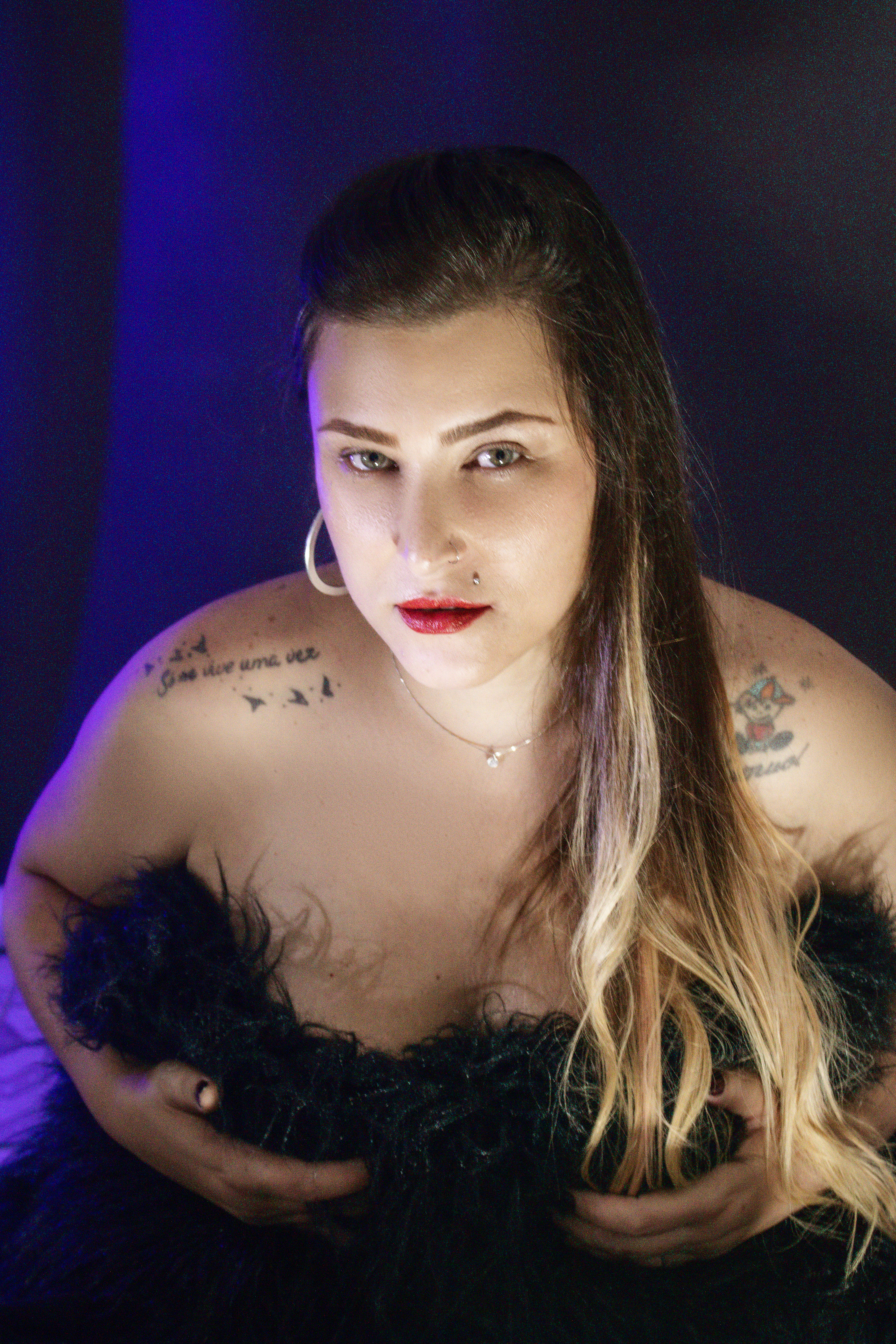 Modern portrait of a tattooed woman in a studio setting, capturing strength and elegance.