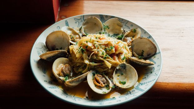 Plate of clams and pasta in a restaurant setting, showcasing a seafood meal.