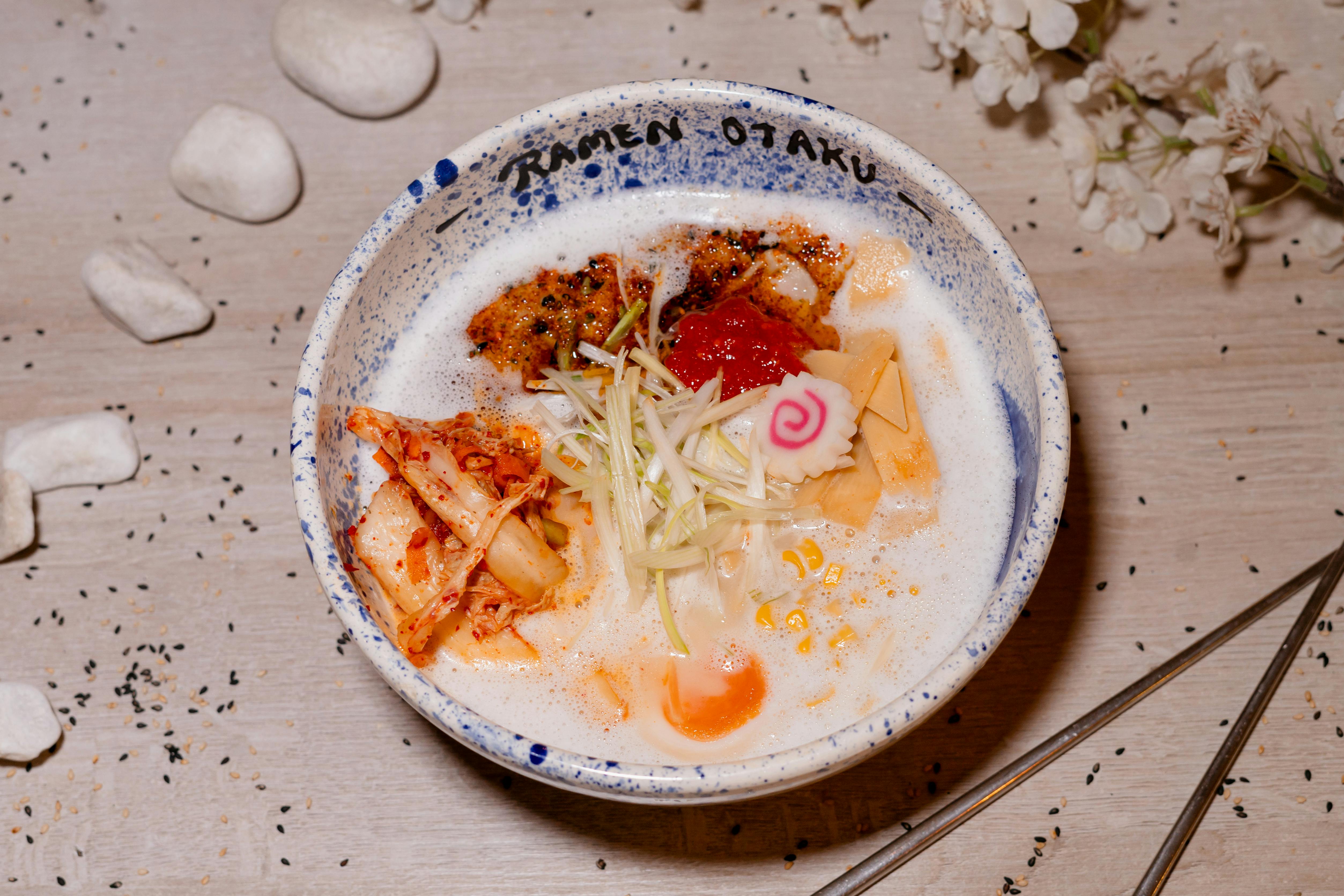 A beautifully arranged bowl of ramen featuring kimchi, egg, and garnish, perfect for a gourmet meal.