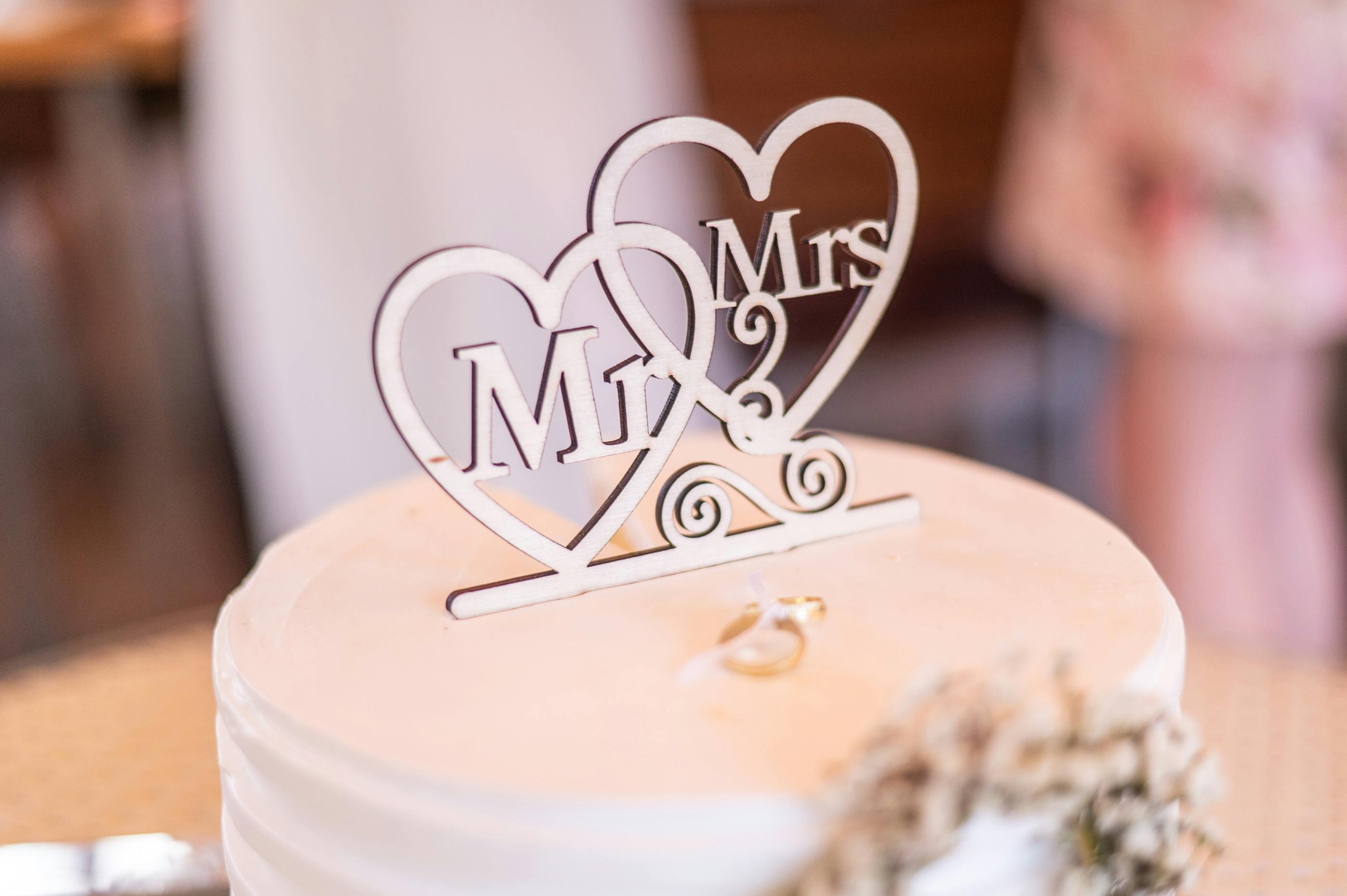 Close-up of a wedding cake with 'Mr & Mrs' topper, symbolizing romance and celebration.