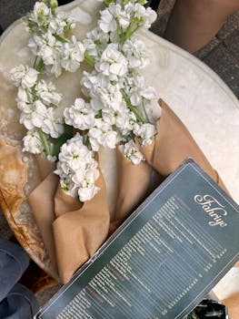 Elegant café table setup with white flowers and a menu.