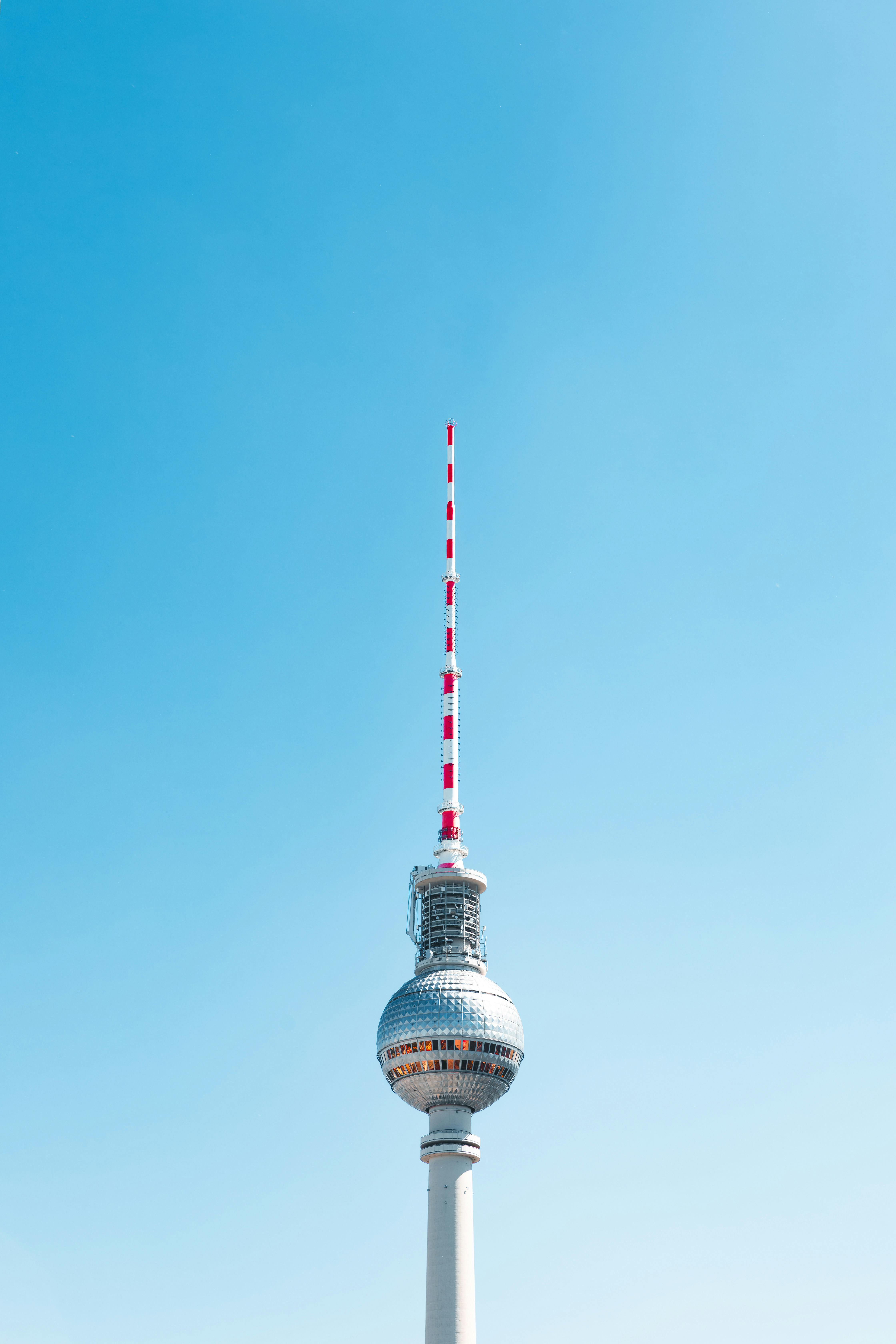 Iconic Berlin TV Tower rising against a cloudless blue sky, creating a striking urban landmark view.