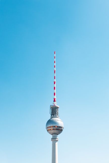 Iconic Berlin TV Tower rising against a cloudless blue sky, creating a striking urban landmark view.