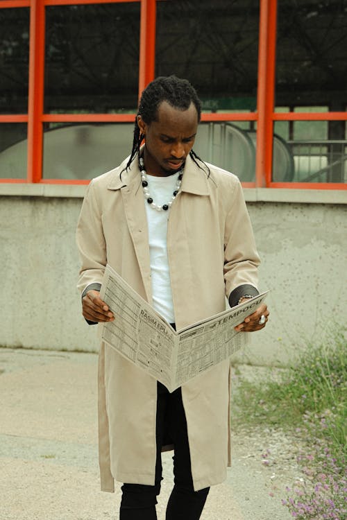 A man in a trench coat reading a newspaper