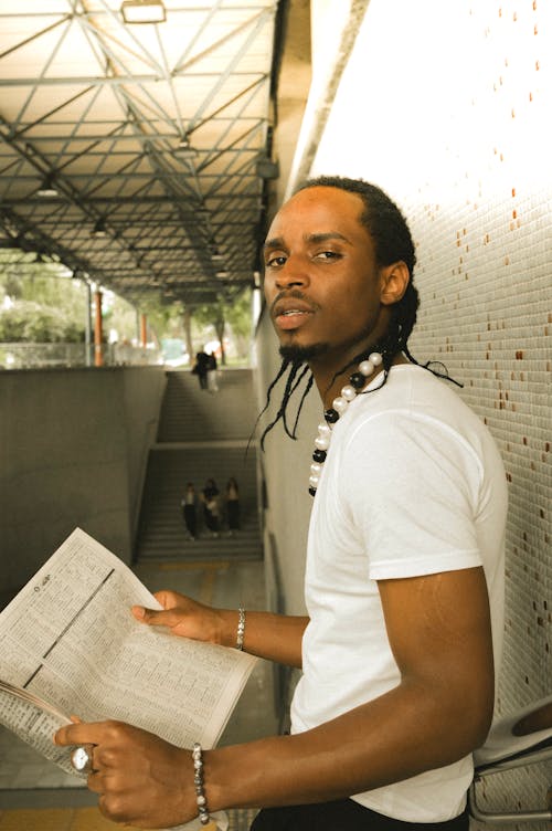 A man with dreads is holding a newspaper