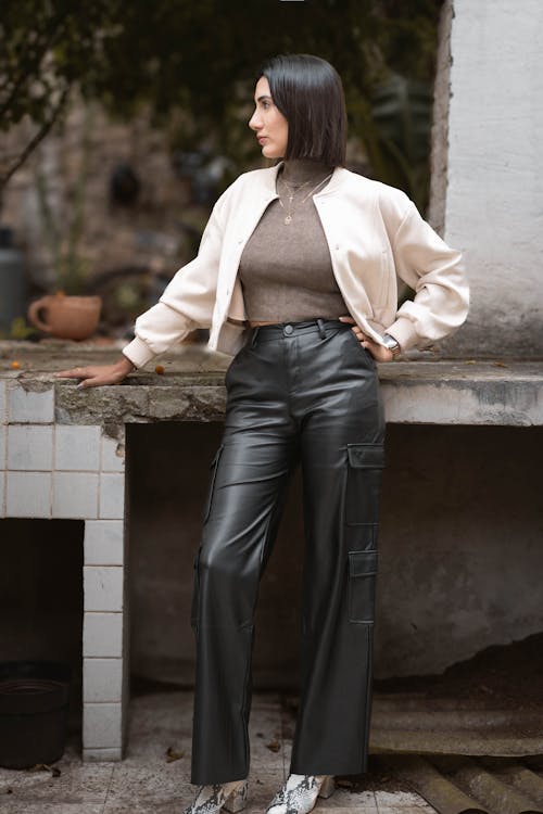 A woman in leather pants and a beige top