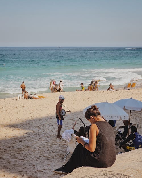 A woman sitting on the beach with a book