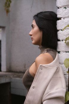 Side view portrait of a woman leaning against a brick wall, captivating expression.