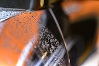 水滴特写视图，背景是模糊的光泽汽车表面