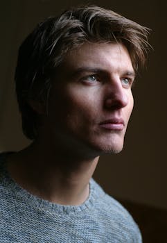 这是一张年轻男子的特写肖像，他在柔和的灯光下神情严肃