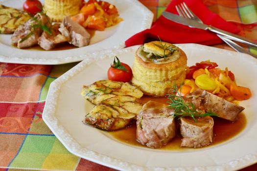Elegant pork tenderloin with vegetables, puff pastry, and tomato garnish, perfect for gourmet dining.