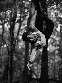 A black and white image of a man performing a fitness routine outdoors, showcasing balance and strength.