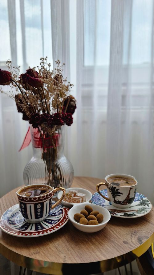 Free Stylish coffee setup featuring ornate porcelain cups, snacks, and a dried floral bouquet on a wooden table. Stock Photo