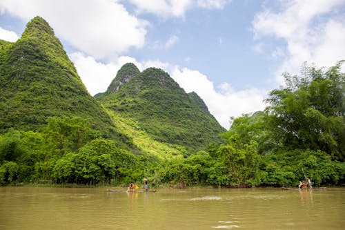 A river with mountains in the background and people on the river