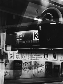 Lisbon subway station with signs and graffiti in black and white.
