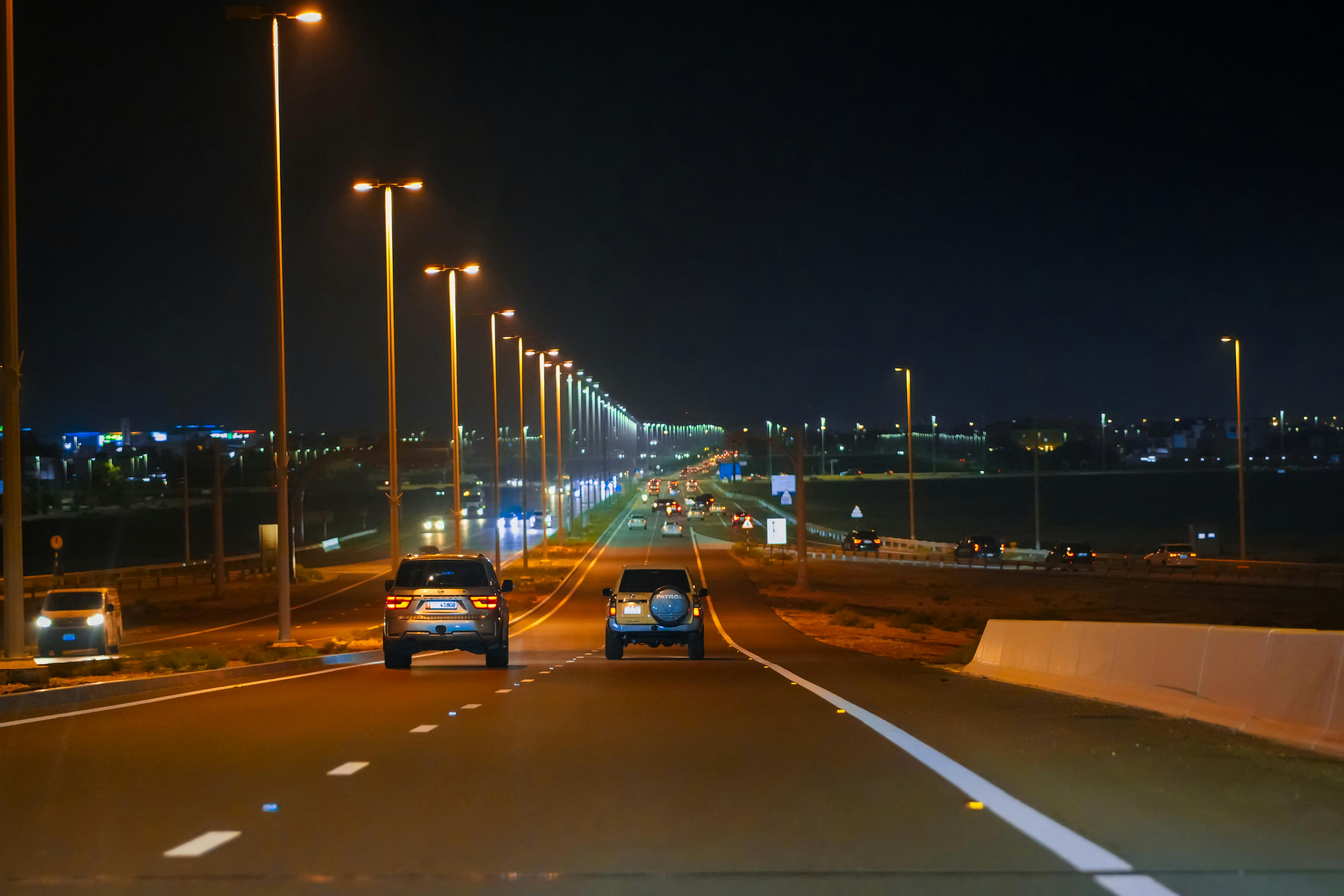 Illuminated highway in Abu Dhabi with cars and streetlights at night.